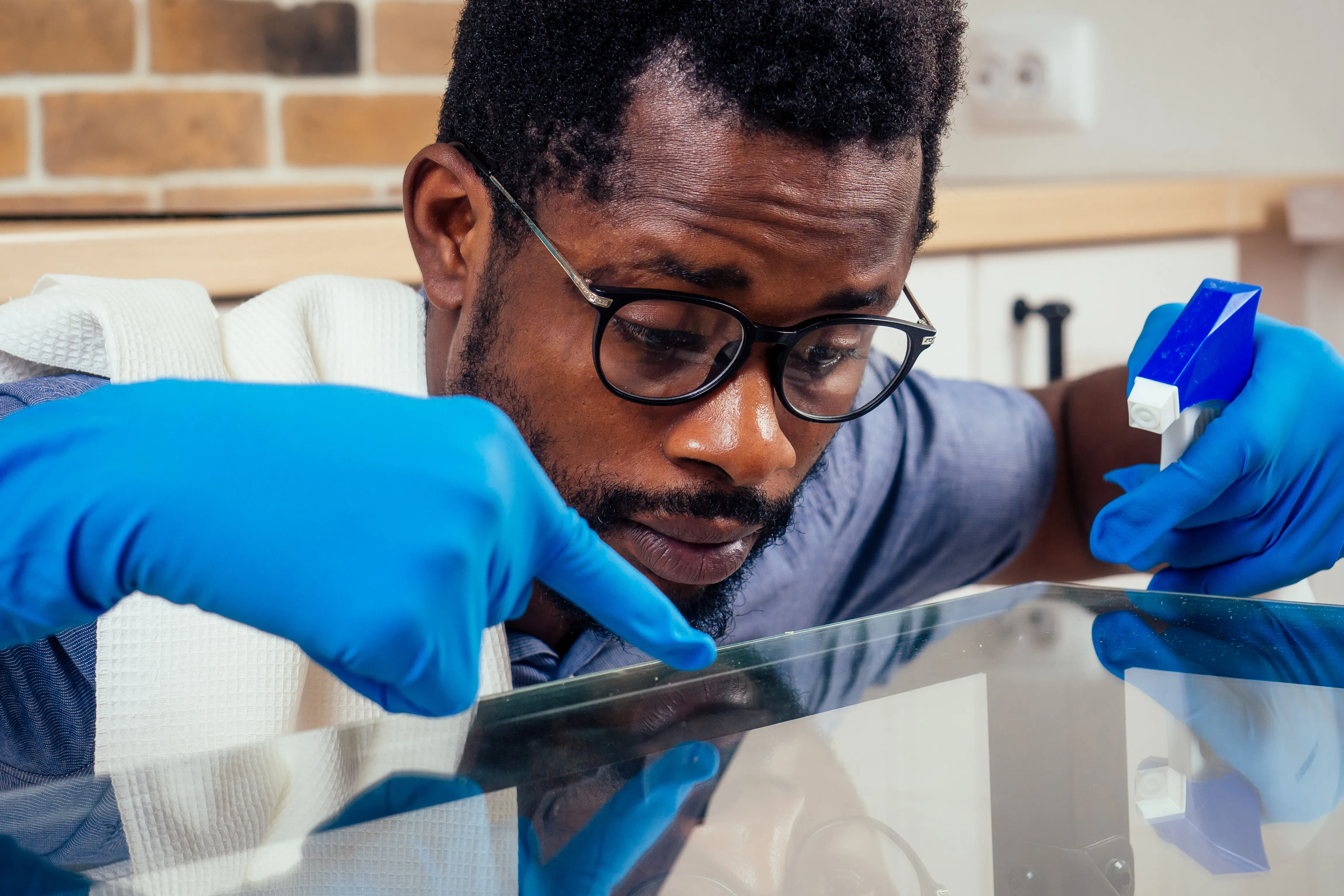 black male cleaning a glass table at home