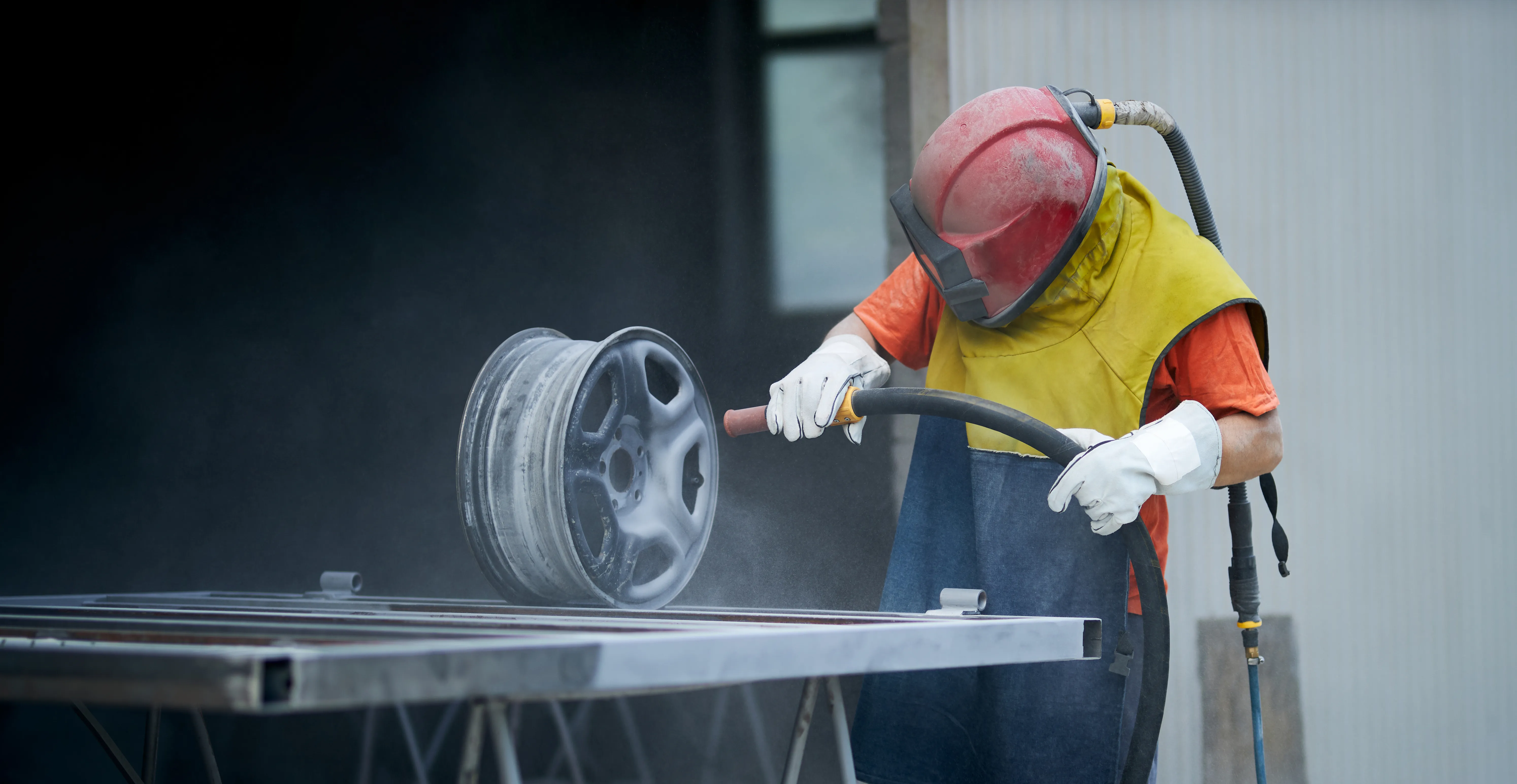 worker sandblasting car rim